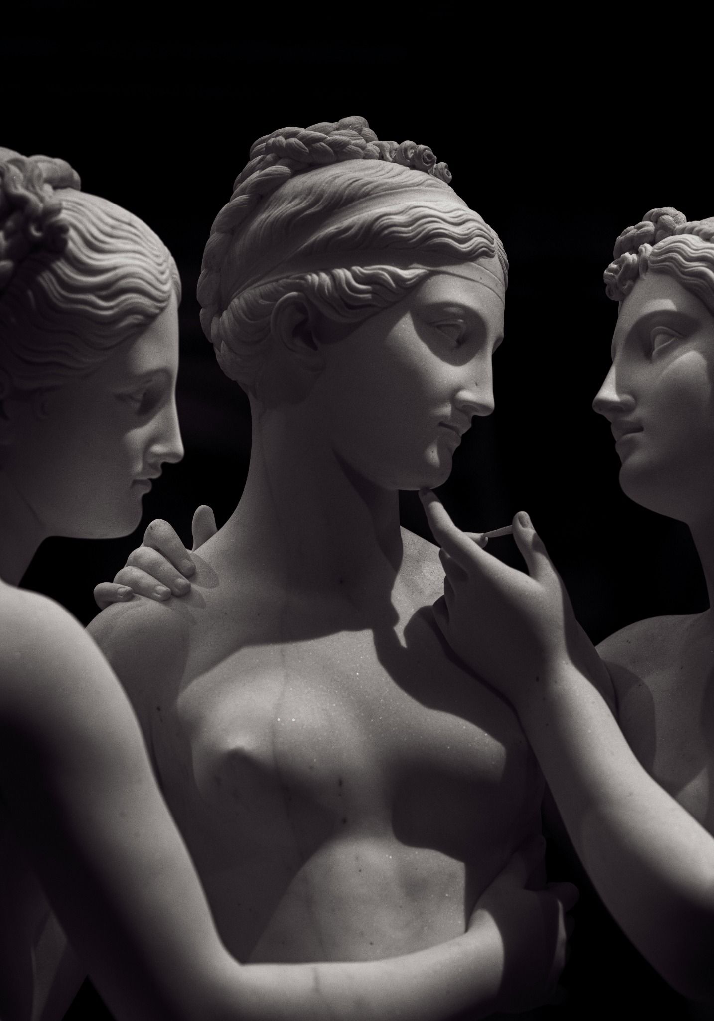 Marble female sculptures against a black background